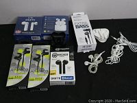 Lot includes new and used earbuds in retail packaging and loose, showing brand boxes for Sony, Wicked Audio, and Athletica Series as well as loose wired earbuds.