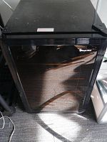Front view of the black Magic Chef mini refrigerator closed, showing the door and brand logo.
