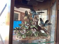 Porcelain bird figurine set on flowering branches in display case