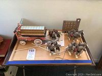 Full setup of the Budweiser wagon pulled by four wooden Clydesdale horses with harnesses on a tabletop.