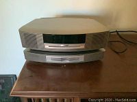 Front view of stacked Bose Wave Music System main unit and CD changer accessory on wood surface.