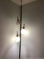 Full view of vintage pole lamp with three frosted glass shades illuminated, showing overall condition and style.