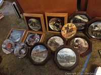 Photo of multiple decorative collectible plates and some wooden plate frames arranged on carpet, featuring trains and western themes.