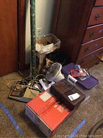 Lot overview showing assortment of electronics, paper shredder, fan, and boxes with CDs and DVDs