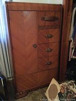 Full view of the mid century wooden wardrobe showing the door and drawer arrangement and the carved wood decoration on the base.