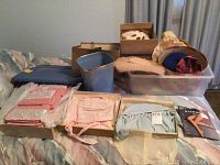 Vintage children’s clothing, hats in boxes, and towels on bed