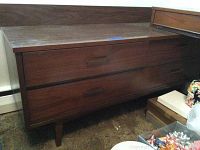 Front view showing the overall dresser design with six drawers, brown wood, and tapered legs.