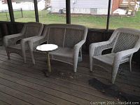 Photo of the entire set of two wicker chairs, loveseat and side table placed on wooden deck flooring.