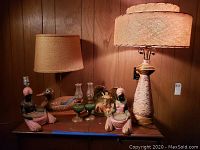 Wide view showing all six lamps and the sea shell crucifix sculpture on a wood surface against wood paneling