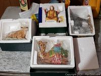 Multiple Franklin Mint nativity figurines including a shepherd and camels in styrofoam boxes on a tabletop.