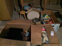 Overview of lot showing child-sized vintage drum set with bass drum and stool, and two boxes containing various items including wooden and plastic toys.