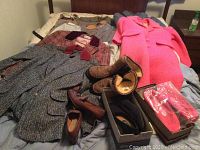 Multiple vintage coats in various colors and patterns and several pairs of shoes and boots displayed on bed.