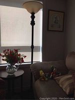 Full view of the 6-foot tall black floor lamp next to a sofa and table with flowers.