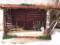 Front angled view of handmade basket manger with natural twig and stone details and striped fabric backing
