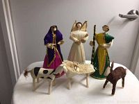 Photo showing hand-crafted nativity figurines including Joseph, Mary, baby Jesus in creche, angel, cow, and donkey