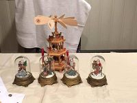 Front view of German wooden Christmas pyramid with four Santa Claus snow globes aligned in front.