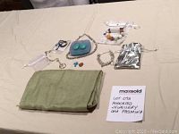 Overview of entire lot including jewellery pieces spread out on a beige surface and a folded green pashmina scarf.