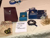 Photo showing the Saoya necklace and Niquea.d bracelet with their original packaging, including velvet and blue pouches and boxes.