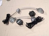 Two bedroom lights with curved arms, plastic lamp covers, and attached cables and wall plugs
