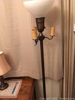 Full view of antique torchiere floor lamp without shade, showing marble base, two candle-style light sockets, and crystal bowl top light