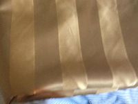 Close-up of gold upholstery fabric showing wide alternating satin and matte stripes