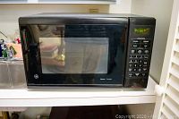 Closed view of black General Electric Sensor microwave oven with control panel on the right side and door to the left.