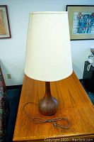 Table lamp assembled with wooden base and white lampshade on wooden table.