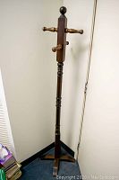 Front view of wooden coat hanger stand showing pegs and base