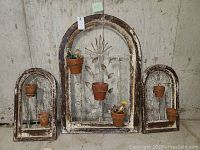 Full view of all three shutter planter art pieces against concrete wall showing sizes, colors, and ceramic planters attached.