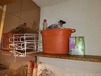 Shelf with large orange metal trash bin, a white wire rack, and a box of Swiffer reusable cloths.