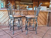 Five matching black iron barstools arranged in front of wooden counter showing overall appearance and height.