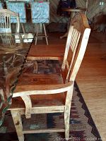 Side view of one carved slatted back chair beside glass tabletop
