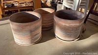 Three concrete planters grouped showing height and size with marbled earth tone finish.