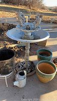 Full view of birdbath, various plant pots and watering can on patio outdoors