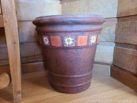 Side view of one terracotta planter with decorative tile band around the rim.
