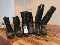 Three pairs of black leather women's boots shown side by side on a wooden floor, including the Harley Davidson boots
