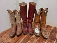 All three pairs of cowboy boots lined up on floor: Frye pair with smooth dark brown leather, Wrangler pair with tan embroidered leather, Rudel pair with light brown leather and stitched patterns.