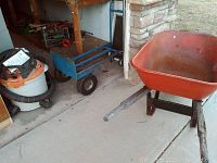 Wheelbarrow, rolling cart dolly, and Shop-Vac vacuum in a garage setting