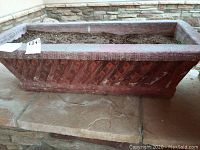 Large rectangular concrete planter box with geometric patterns, filled with soil, showing weight and condition