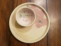 Main photo of pottery plate with smaller dip bowl placed inside, showing color pattern and finish.