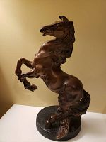 Photo of bronze rearing stallion sculpture showing full body and stance on round base.