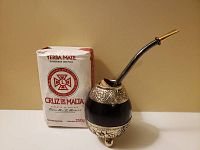 Full view of the gourd and bombilla next to a package of yerba mate for size reference.