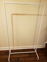 Front view of white metal clothes rack showing single horizontal bar and base.