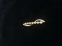 Front view of diamond pendant showing seven round diamonds set in curved yellow gold setting.