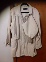 Front view of light beige APROPOS winter jacket, showing collar, front pockets, and zip closure with the hood hanging on the side.