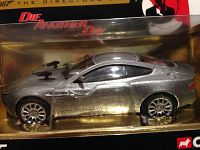 Side view of silver diecast Aston Martin Vanquish with firing rockets in original packaging, highlighting detailed wheels and body shape.