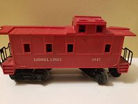 Side view of red Lionel Lines caboose model 6047 showing windows, raised cabin, and black railings.