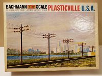 Box front of Bachmann O-S Scale Plasticville Hydro Poles model train set showing colorful artwork of utility poles against a city skyline and railway.