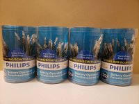 Four cylindrical clear plastic containers each holding a set of Philips battery operated warm white mini string lights.