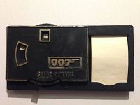 Front view of the James Bond Code O Matic Decoder black plastic toy showing the 007 logo, window labeled 'Press Letter,' and paper slot to decode messages.